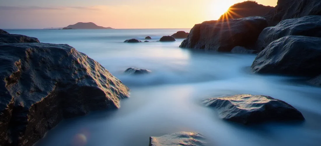 Photo avec mouvement d'une côte rocheuse à l'aube, l'eau de mer rendue soyeuse par une pose longue autour de rochers noirs