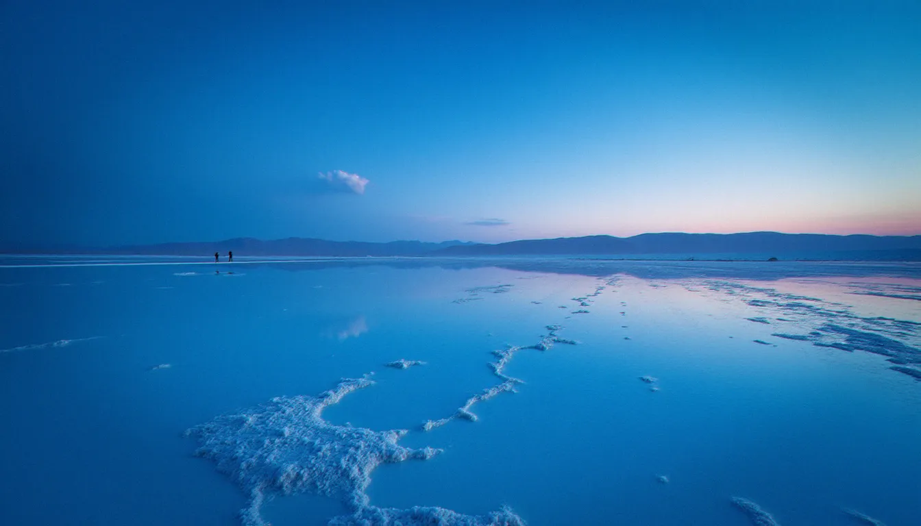 Désert de sel du Dasht-e Kavir en Iran à l'heure bleue, reflet du ciel sur les cristaux de sel, atmosphère minimaliste caractéristique des sorties photo en Iran à l'aube